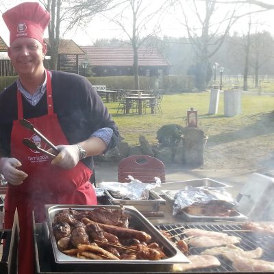 Kulinarik im Gut Landegge: Das Fleisch brutzelt auf dem Grill. Der Koch mit Kochmütze und Schürze lächelt in die Kamera.